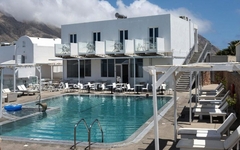 Hotelpool mit Liegestühlen und weißen Gebäuden im Hintergrund.