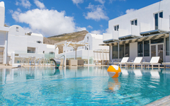 Poolbereich des Iliada Odysseas Resorts auf Santorin mit Liegen und buntem Wasserball