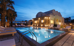 Außenansicht eines beleuchteten Resorts mit Pool bei Abenddämmerung.