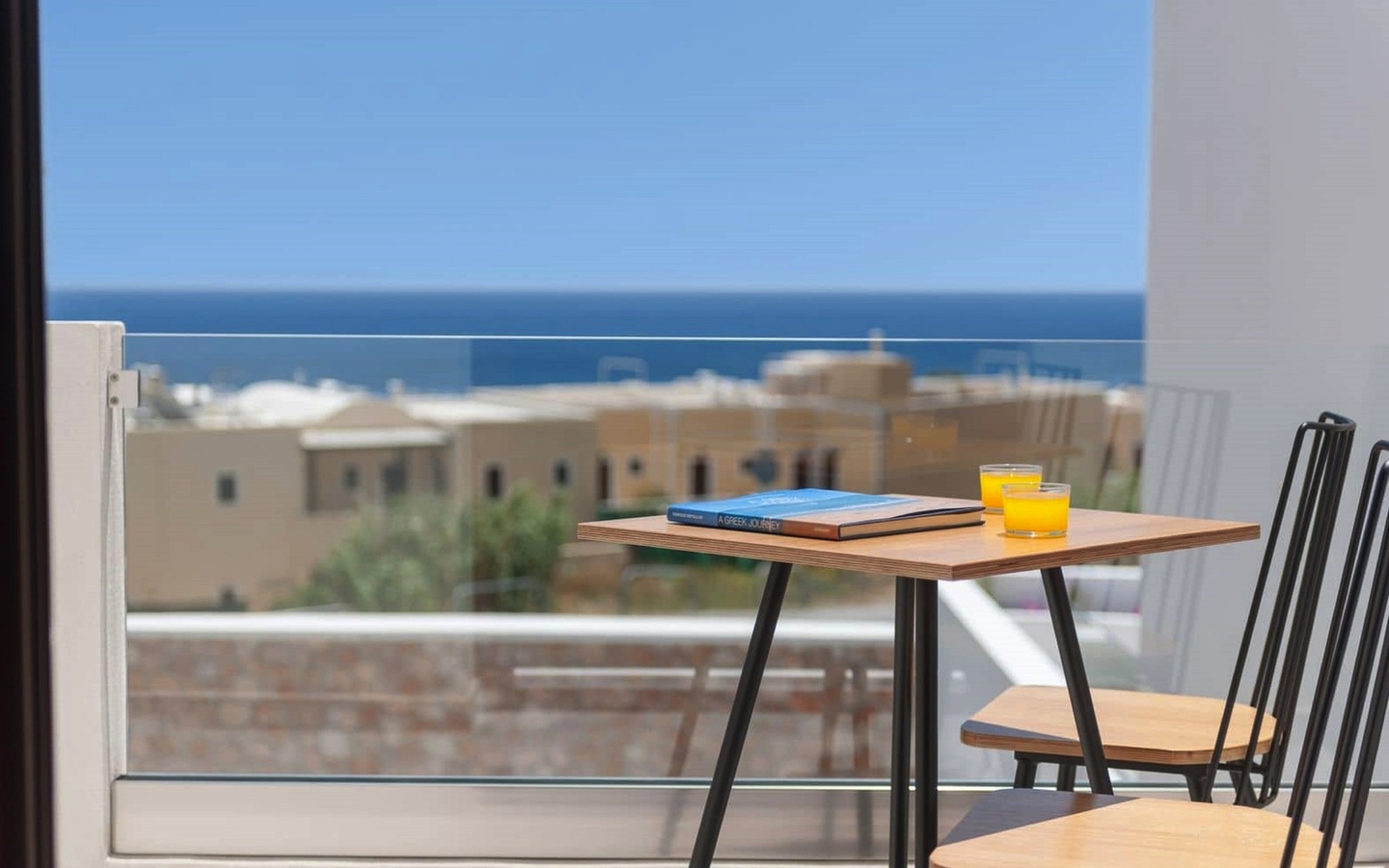 Blick von einem Balkon mit Tisch und Stühlen auf das Meer in Santorin, Griechenland.