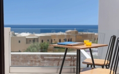 Blick von einem Balkon mit Tisch und Stühlen auf das Meer in Santorin, Griechenland.