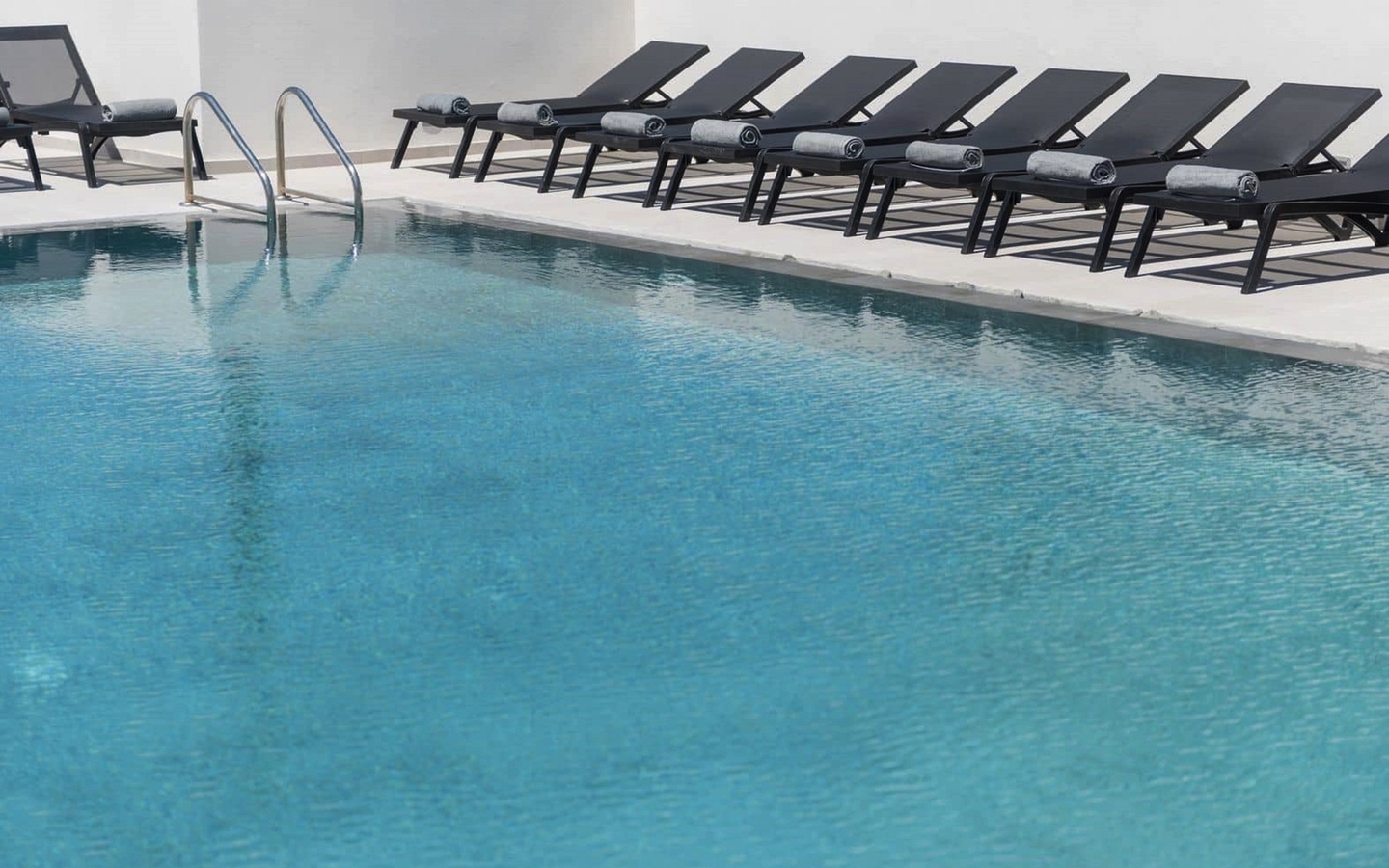 Pool mit blauen Liegestühlen und Leiter am Beckenrand.