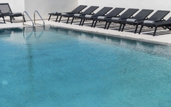 Pool mit blauen Liegestühlen und Leiter am Beckenrand.