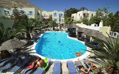 Hotelpool mit Liegestühlen und Palmen, umgeben von mediterranen Gebäuden.