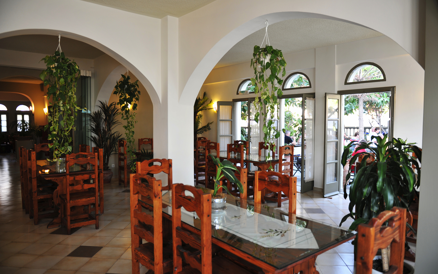 Hotelrestaurant mit Holztischen und Pflanzen in Santorin, Griechenland.