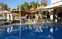 Swimmingpool des Hotels Hermes auf Santorin mit Sonnenschirmen und Palmen.