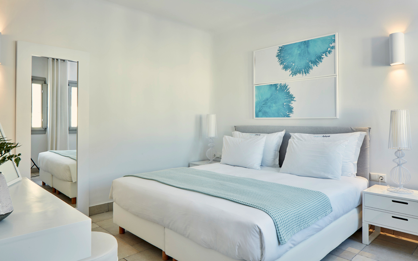 Modernes Hotelzimmer mit Doppelbett, weißen Wänden und blauer Dekoration.