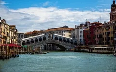 Rialtobrücke in Venedig über dem Canal Grande bei sonnigem Wetter.