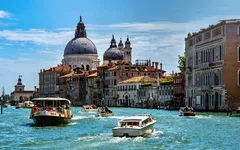 Boote auf einem Kanal vor historischen Gebäuden in Venedig.