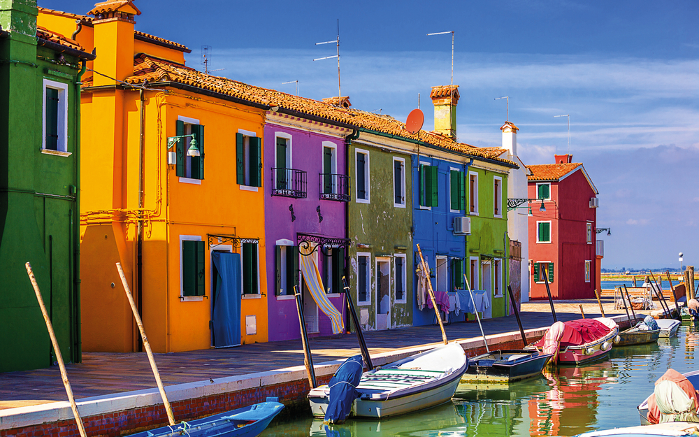 Bunte Häuser und Boote am Hafen von Burano, Venedig.