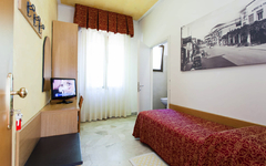 Einzelzimmer in einem Hotel mit Bett, TV und großem Fenster.