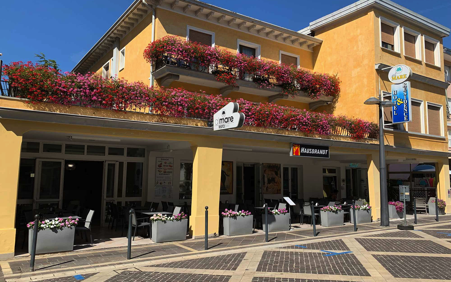 Gelbes Hotelgebäude mit blühenden Balkonen in Venedig, Italien.