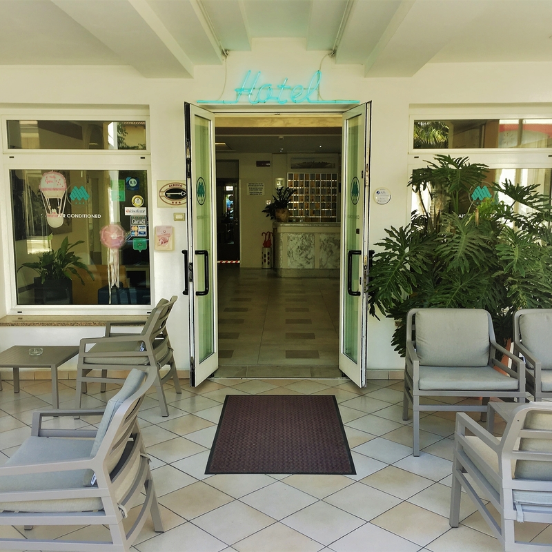 Eingang eines Hotels mit Sitzgelegenheiten und Pflanzen im Vordergrund.