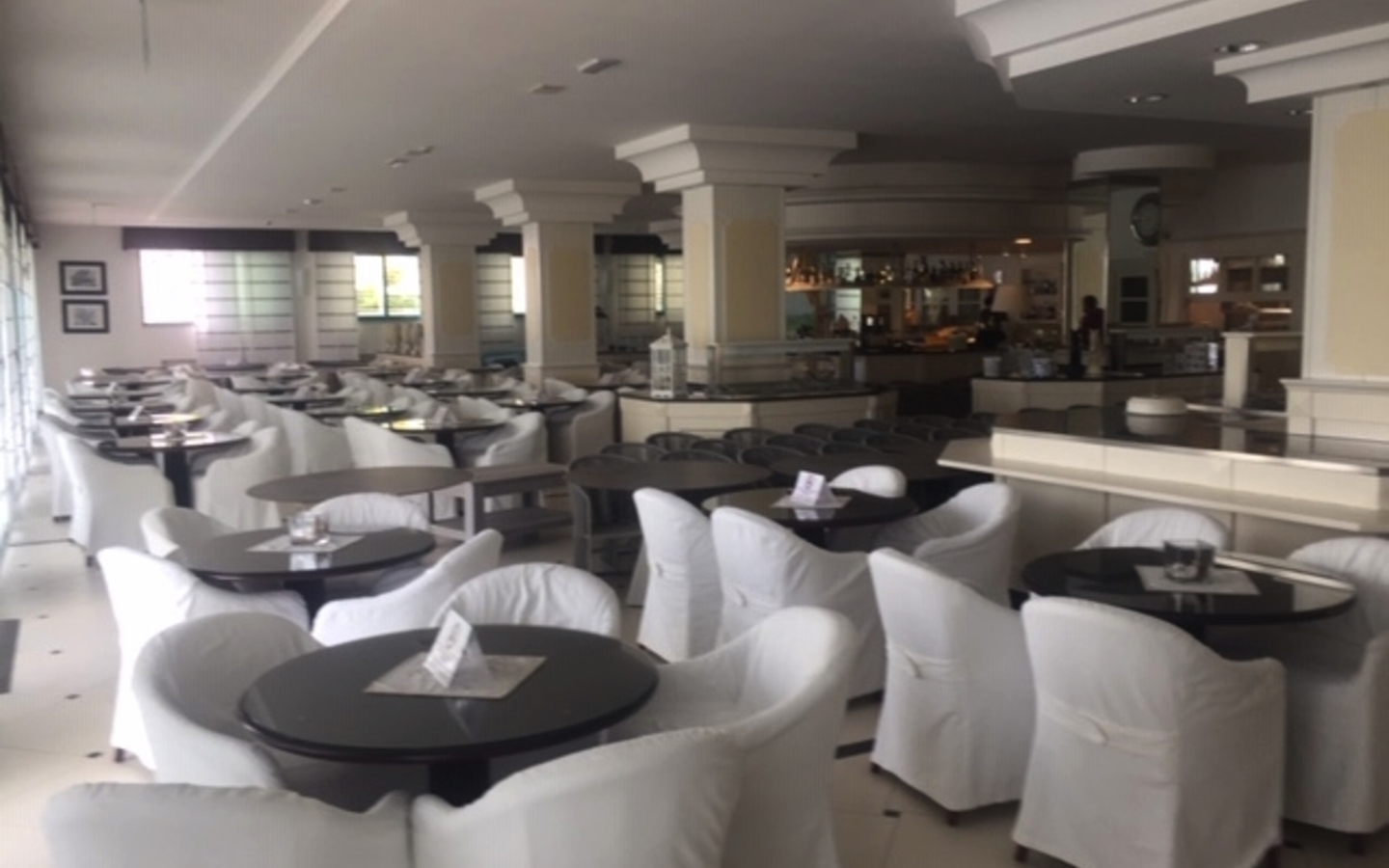 Helles Restaurant mit weißen Tischen und Stühlen, moderner Inneneinrichtung.