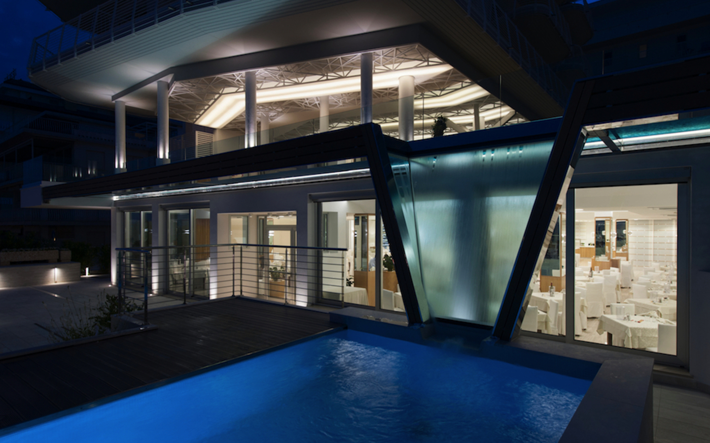 Beleuchtetes Hotel mit Pool bei Nacht.