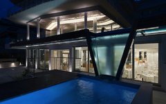 Beleuchtetes Hotel mit Pool bei Nacht.