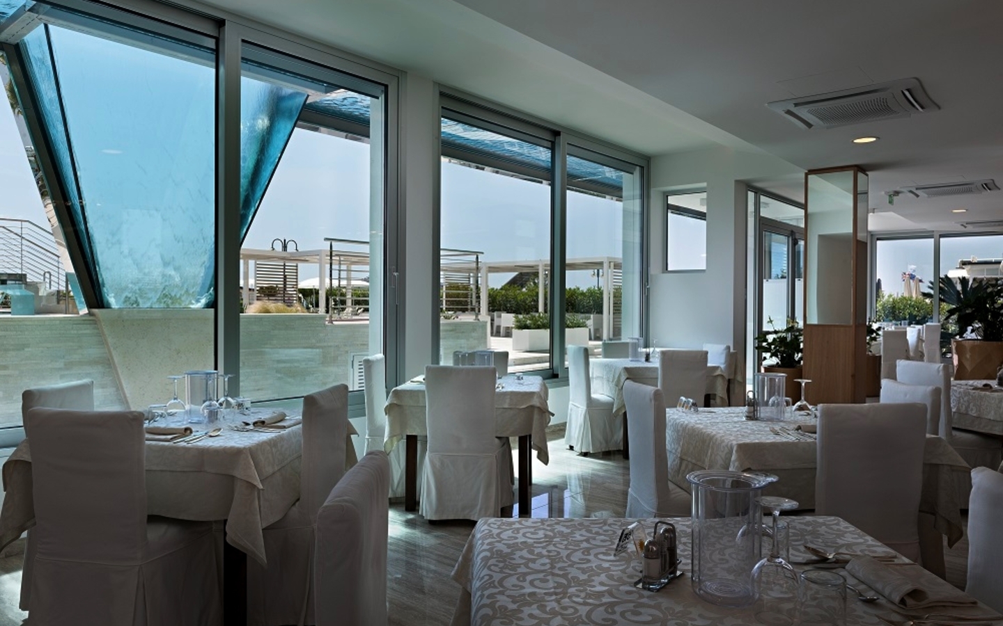 Helles Restaurant mit gedeckten Tischen und Blick nach draußen.