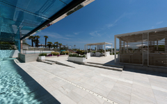 Hotelpool im Freien mit modernen Sitzbereichen unter freiem Himmel und Palmen im Hintergrund