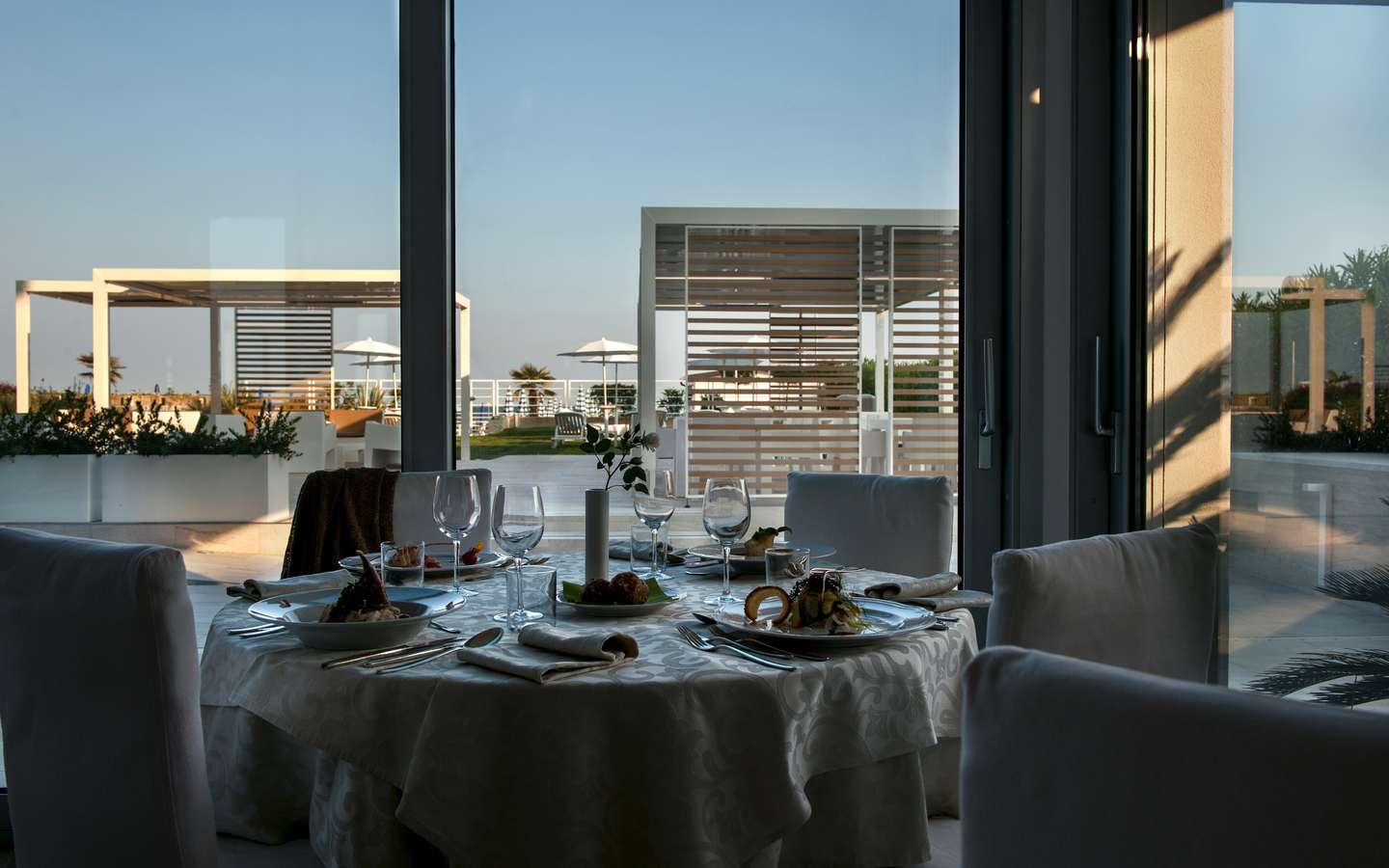 Restauranttisch mit gedecktem Geschirr vor modernen Terrassenfenstern