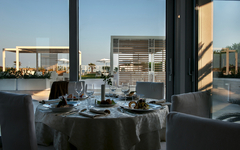Restauranttisch mit gedecktem Geschirr vor modernen Terrassenfenstern