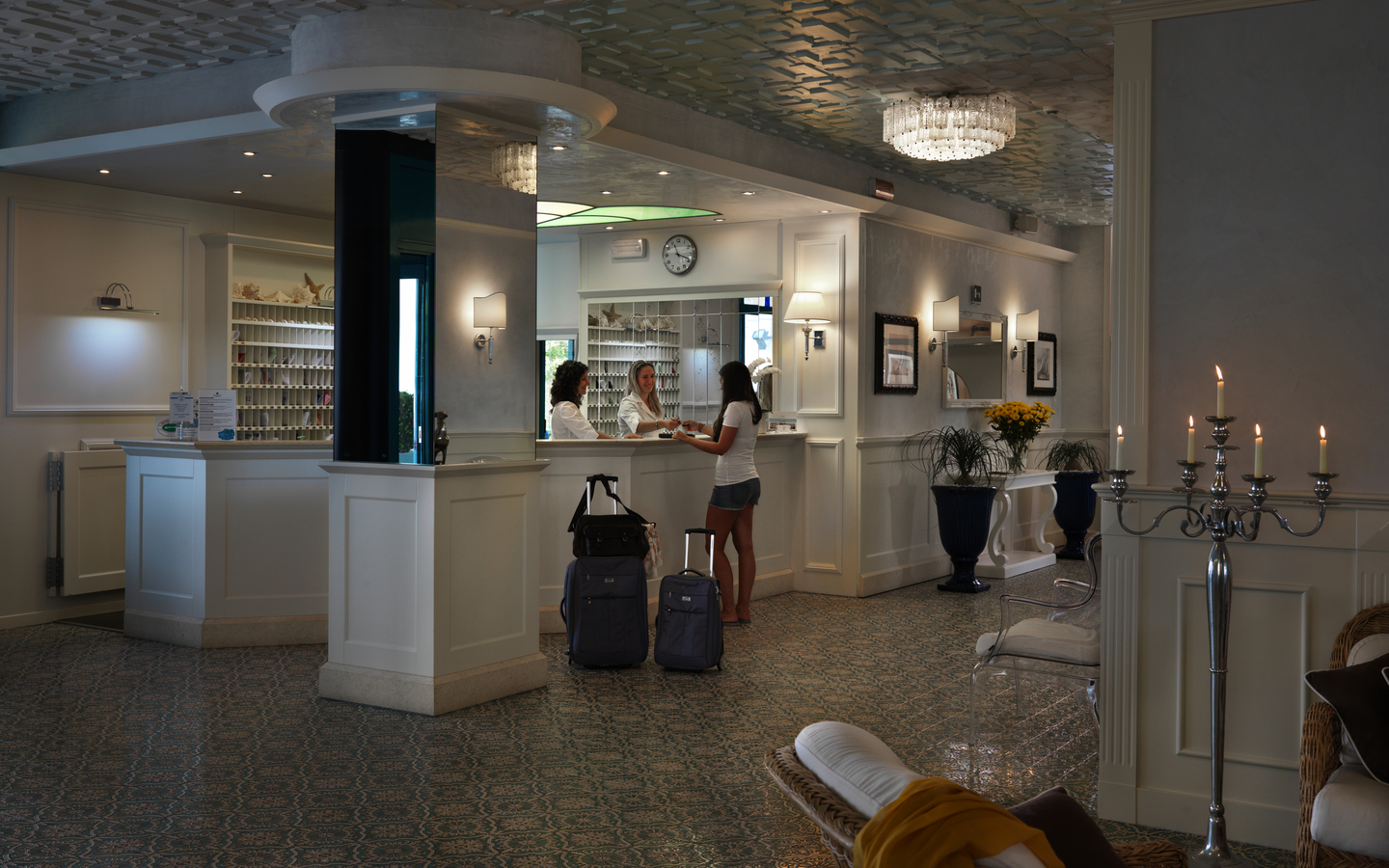 Hotelrezeption mit zwei Gästen und Gepäck im eleganten Raum.