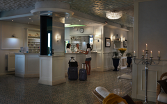 Hotelrezeption mit zwei Gästen und Gepäck im eleganten Raum.