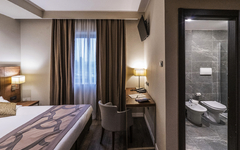 Modernes Hotelzimmer mit Doppelbett, Schreibtisch und angrenzendem Badezimmer.