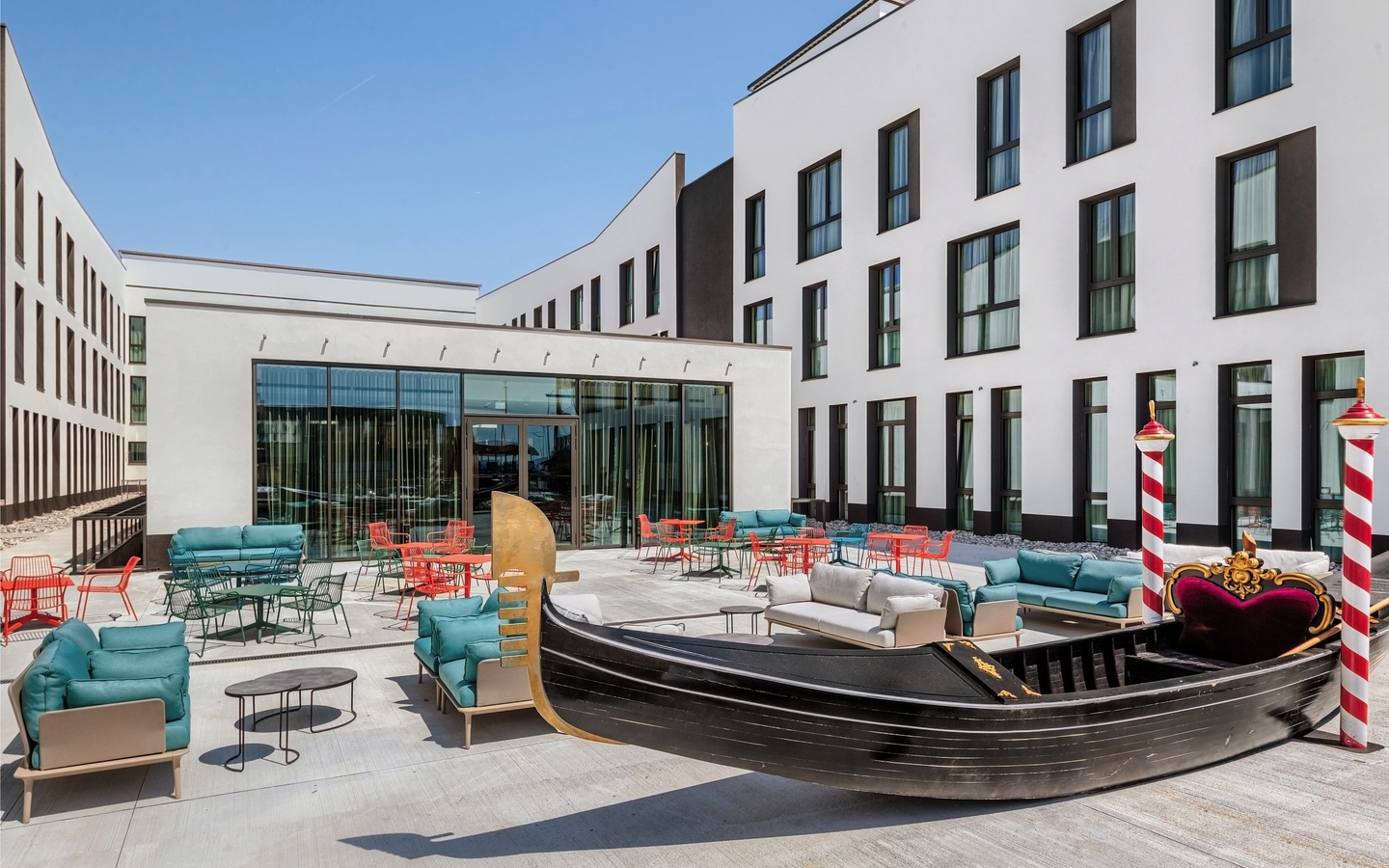 Terrasse des Hampton by Hilton Venice mit Sitzgelegenheiten und Dekogondel.