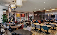 Modernes Hotelrestaurant mit bunten Stühlen und dekorativen Wänden.