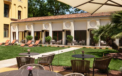 Gartenbereich eines Hotels mit Tischen, Stühlen und Liegestühlen.