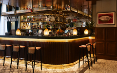 Elegant eingerichtete Hotelbar mit Hockern und beleuchtetem Tresen.