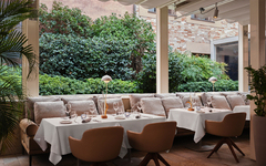 Außenbereich eines Restaurants mit gedeckten Tischen und grüner Umgebung.