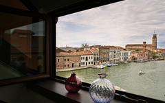 Blick aus einem Fenster auf Murano, Venedig, mit bunten Glasvasen im Vordergrund.