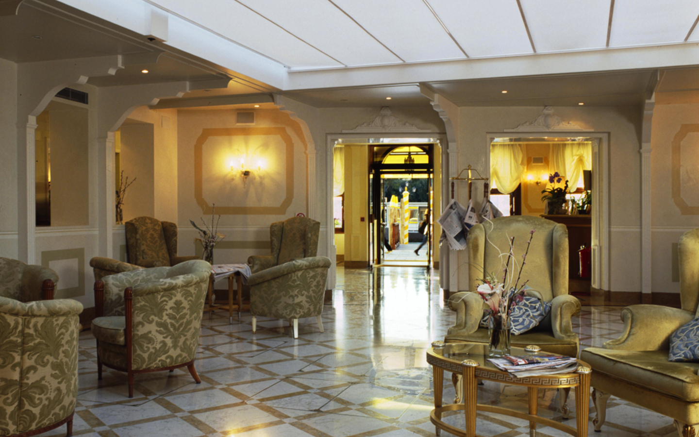 Hotel-Lobby mit eleganten Sesseln und Tisch auf glänzendem Marmorboden.