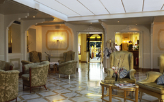 Hotel-Lobby mit eleganten Sesseln und Tisch auf glänzendem Marmorboden.