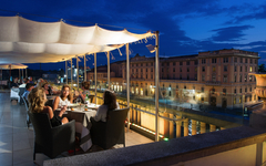 Terrasse eines Hotels bei Abenddämmerung mit Gästen beim Essen, Blick auf Gebäude in Venedig.
