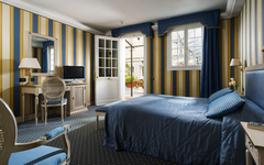Hotelzimmer mit blauer Bettwäsche, TV, Schreibtisch und blick nach draußen.
