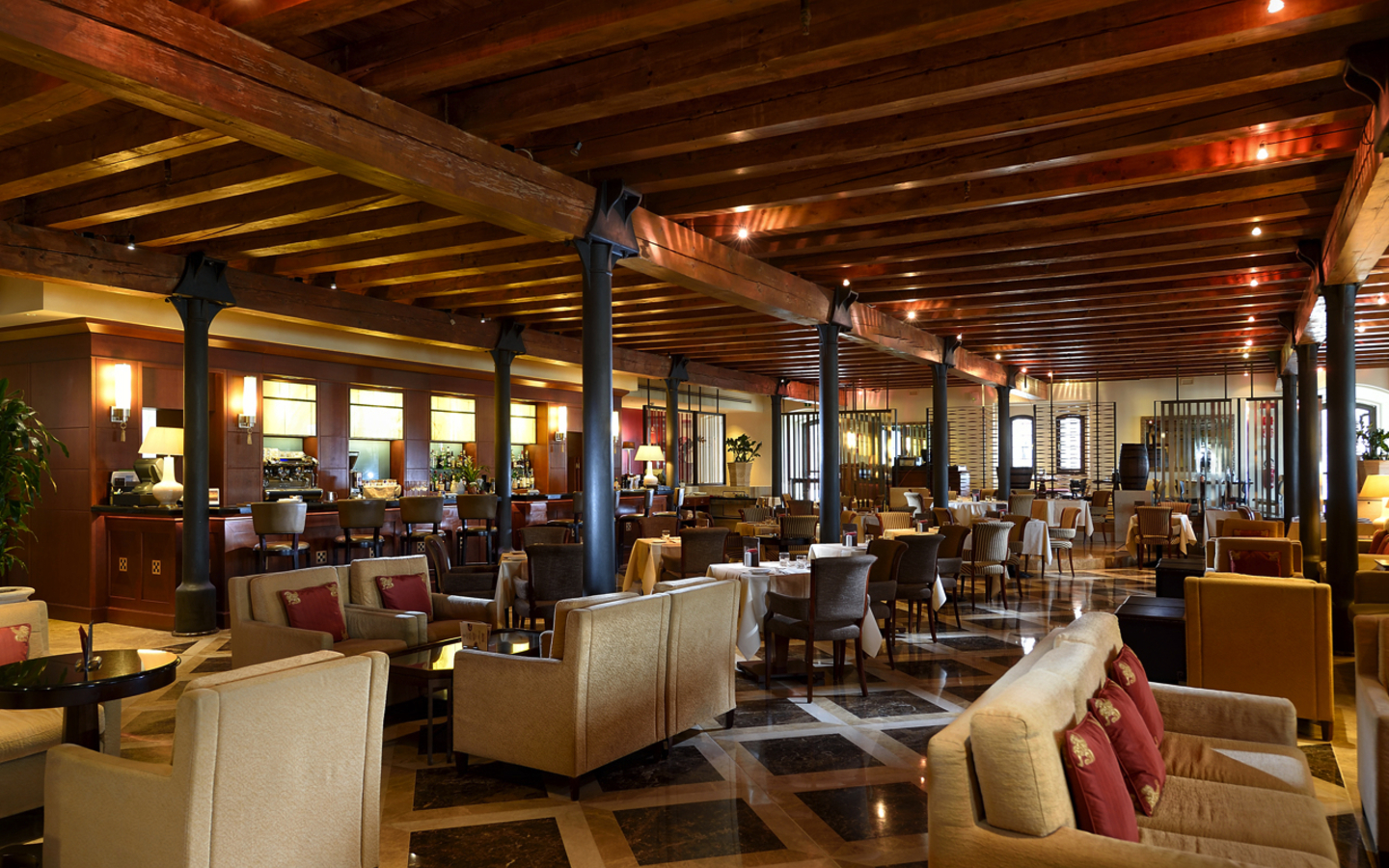 Geräumige Lobby-Bar mit Holzbalkendecke, gemütlichen Sitzbereichen und stilvoller Einrichtung.