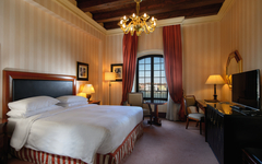 Luxuriöses Hotelzimmer mit Doppelbett, Kronleuchter und großem Fenster.