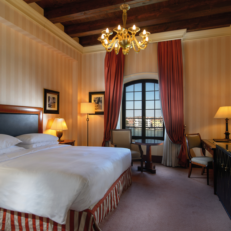 Luxuriöses Hotelzimmer mit Doppelbett, Kronleuchter und großem Fenster.