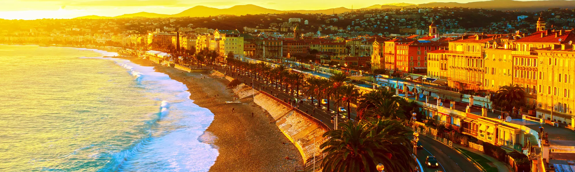 Strand und Stadtpanorama von Nizza bei Sonnenuntergang, Côte d’Azur, Frankreich.