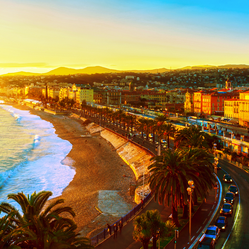 Strand und Stadtpanorama von Nizza bei Sonnenuntergang, Côte d’Azur, Frankreich.