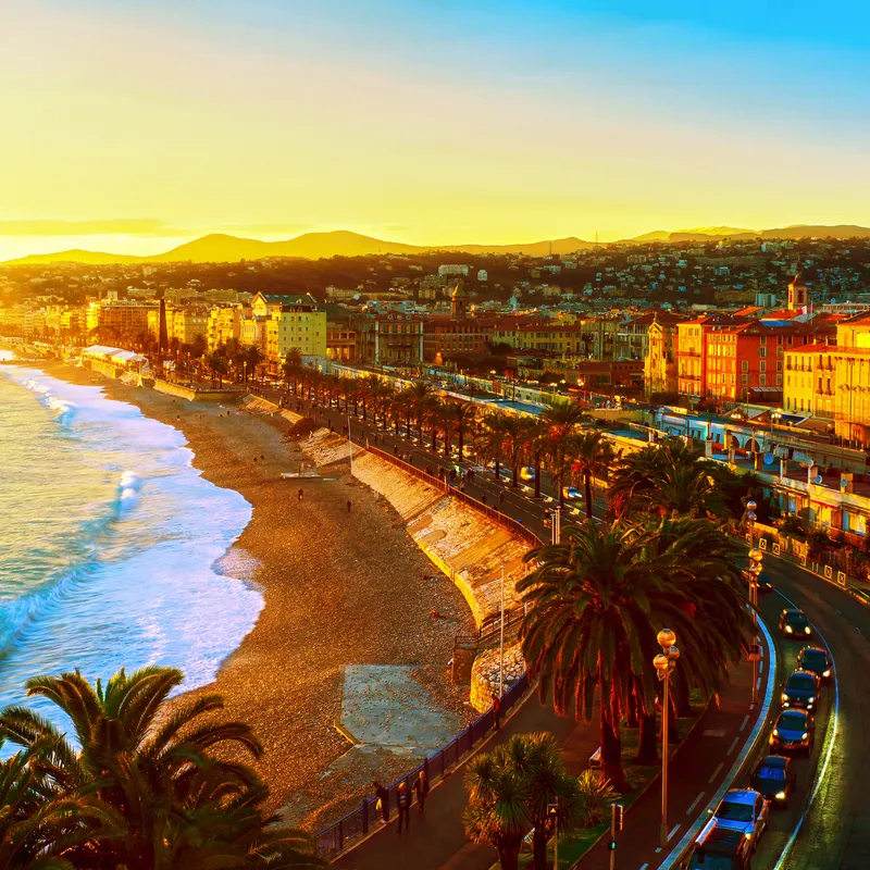 Strand und Stadtpanorama von Nizza bei Sonnenuntergang, Côte d’Azur, Frankreich.