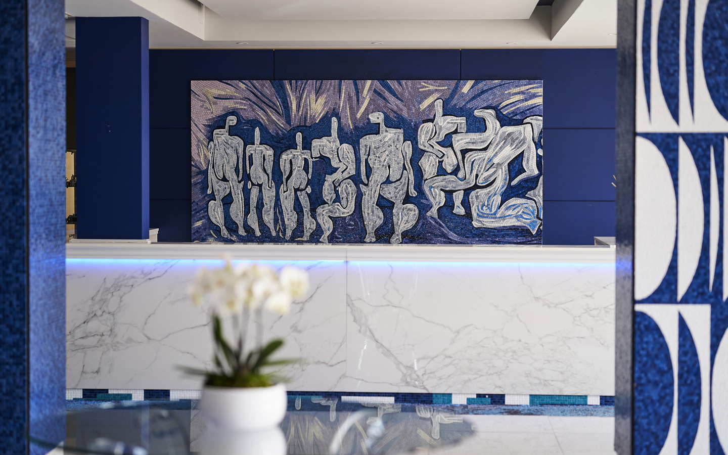 Moderne Hotel-Lobby mit Kunstwerk an der Wand und Orchidee im Vordergrund.