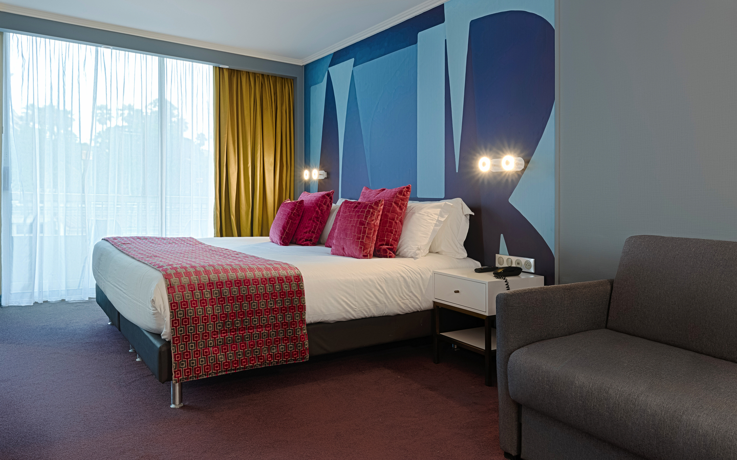 Modernes Hotelzimmer mit Bett, Sofa und großen Fenster.