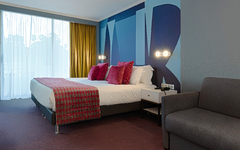Modernes Hotelzimmer mit Bett, Sofa und großen Fenster.