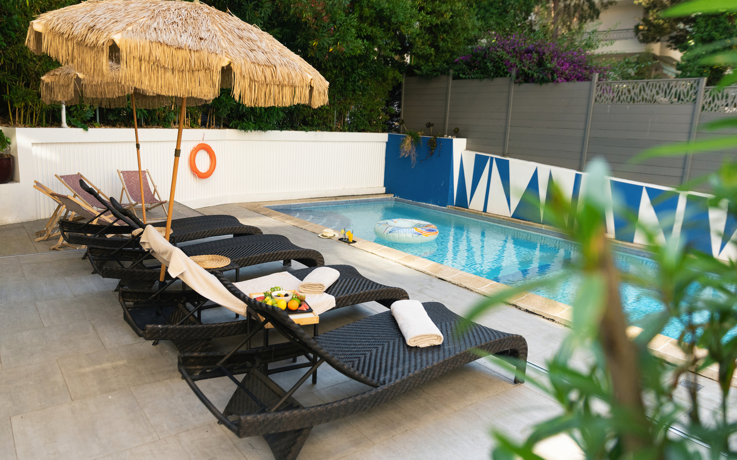 Sonnenschirme und Liegestühle am Pool in einem Hotelgarten.