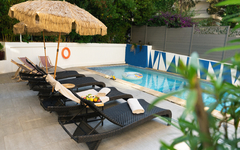 Sonnenschirme und Liegestühle am Pool in einem Hotelgarten.