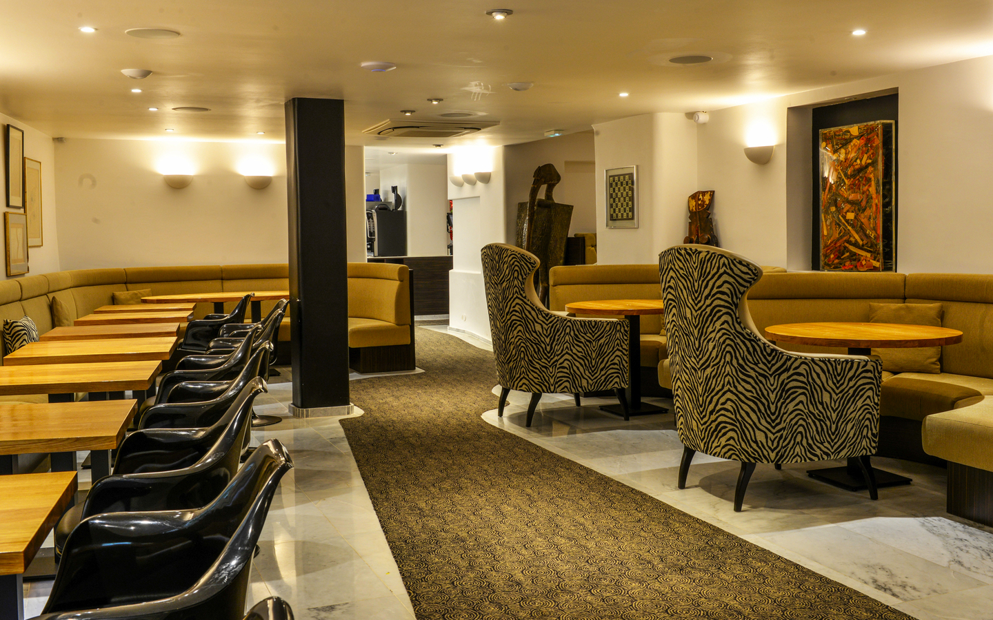 Innenansicht eines modernen Hotelrestaurants mit Tischen und gepolsterten Sitzecken.