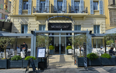 Fassade eines Hotels mit Glasfront und Außenbereich im Erdgeschoss.
